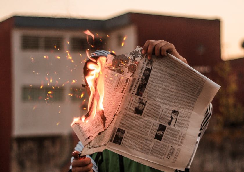 person in green jacket burning newspaper